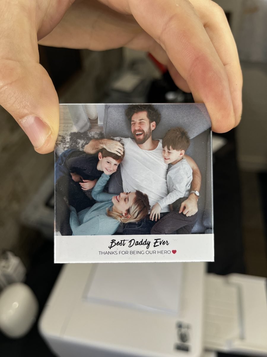 Hand holding a finished custom photo magnet of a family