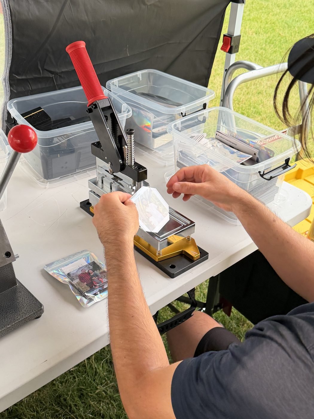 Live Magnets Co. team member pressing a custom photo magnet on-site at an event